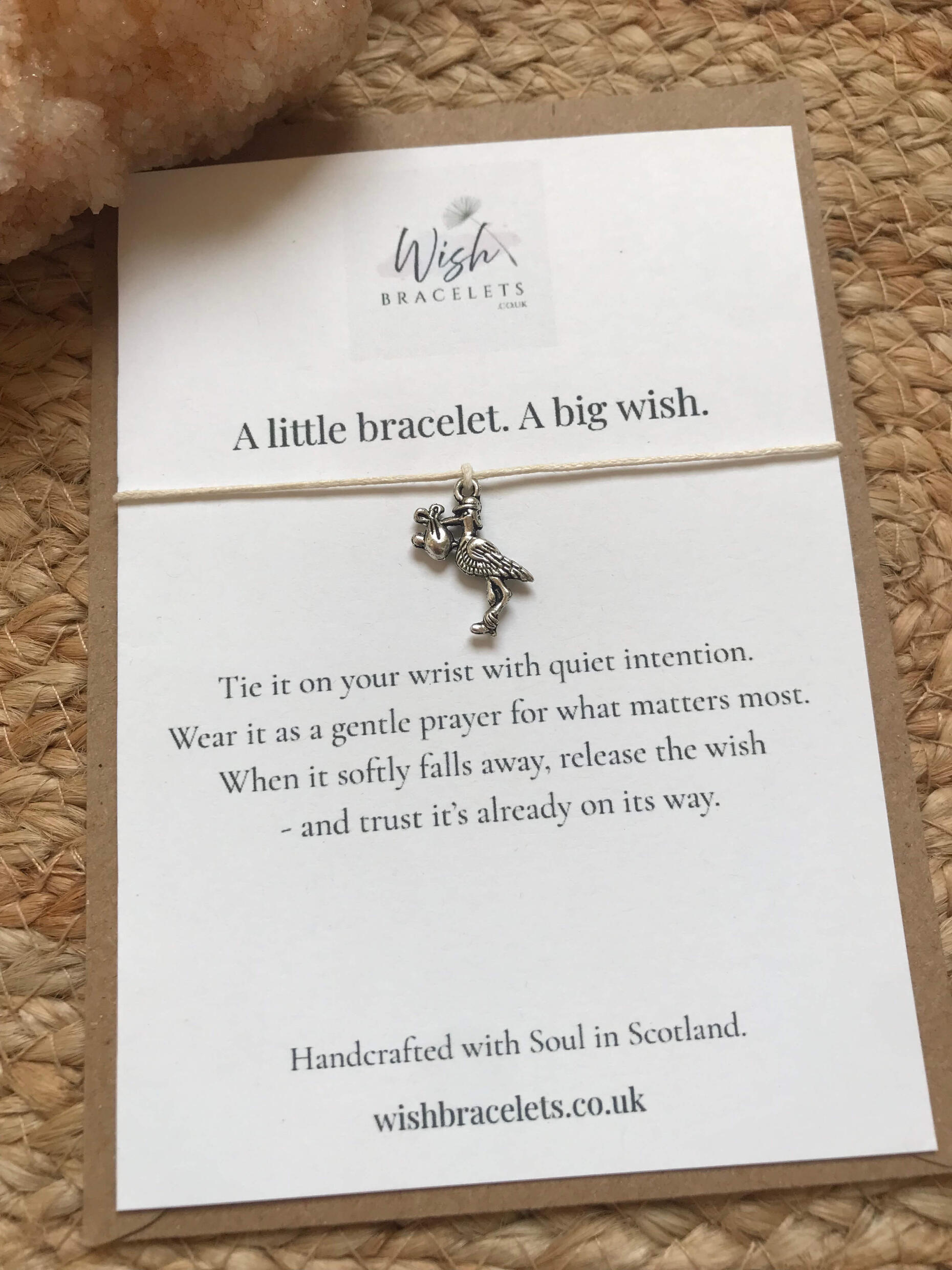 Tiny Miracles Wish Bracelet wish bracelet featuring a stork carrying a baby on an amethyst crystal background